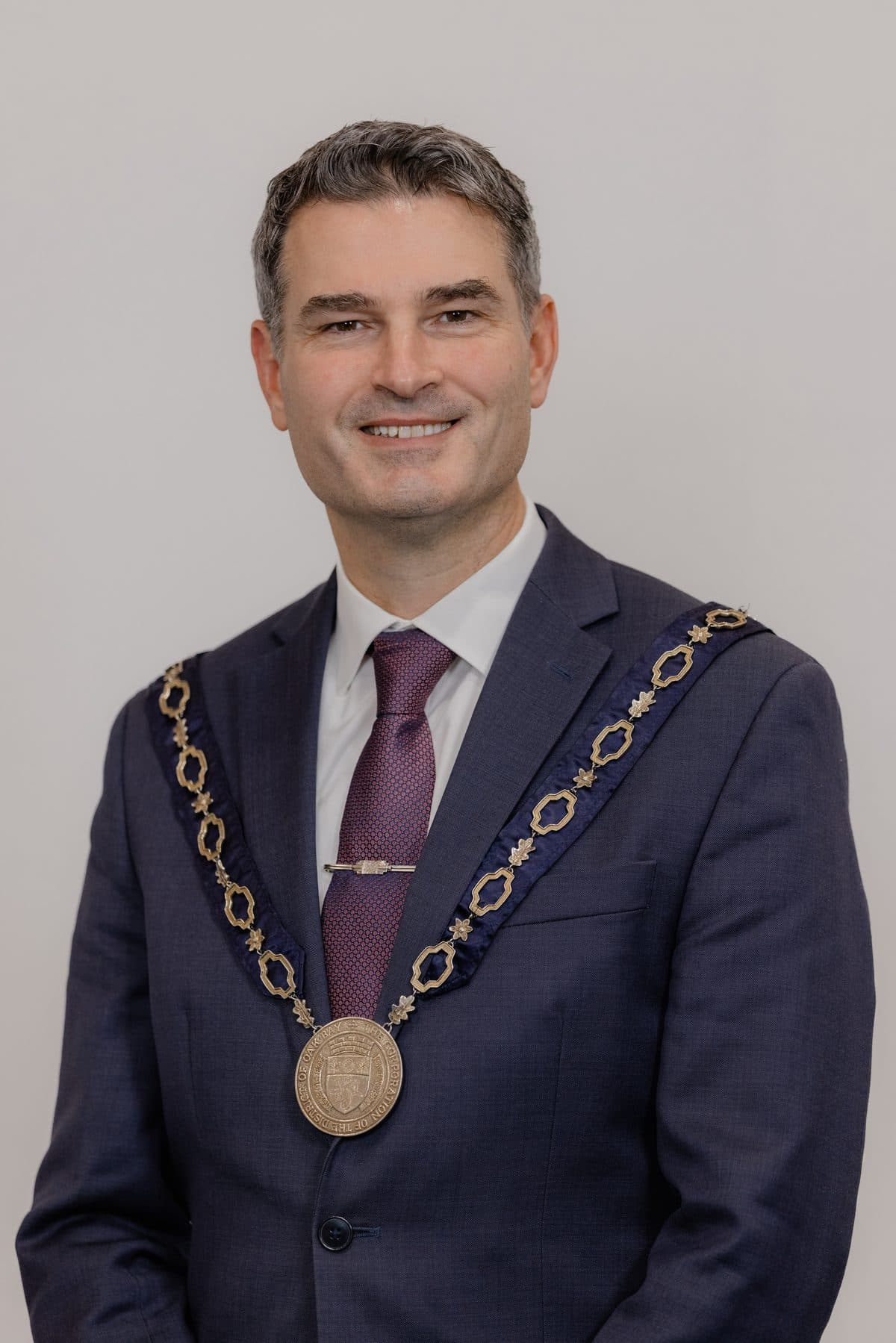 Kevin Murdoch, mayor of Oak Bay, wearing a dark suit, burgundy tie and the mayoral chain of office